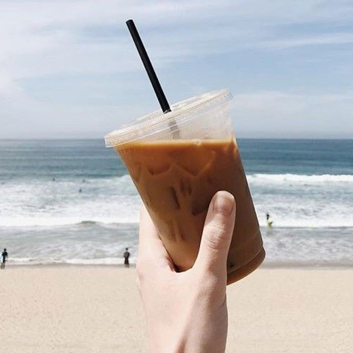 hand holding a cold brew coffee with the ocean in the background